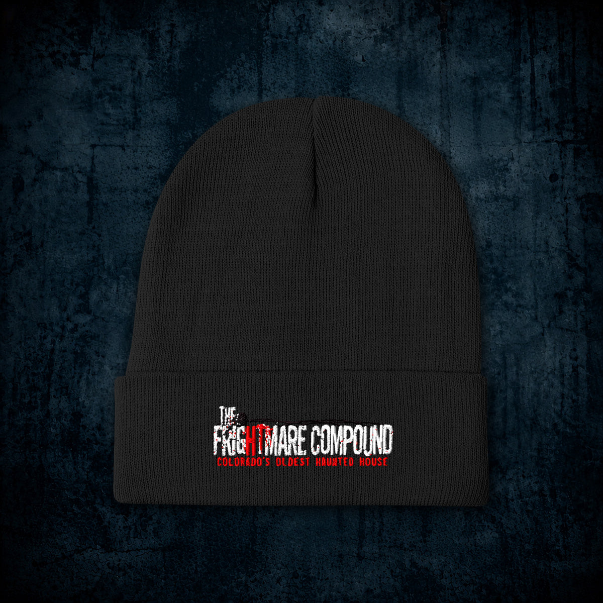 A black ribbed knit beanie hat with a folded cuff, featuring a white and red embroidered logo that reads 'The Nightmare Compound' and 'Criminally Wrongly Hated House' on a dark textured blue background.